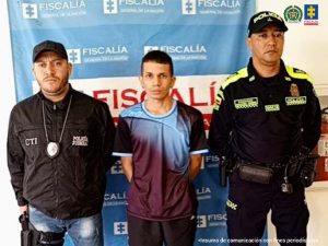 En la fotografía se aprecia de pie y con los brazos atrás a Elkin Andrey Henao Zapata. Viste camisa de manga corta color uva con azul, pantalón negro y zapatilla blancas. Al lado derecho de él hay un servidor del CTI de la Fiscalía. Al lado izquierdo hay un uniformado de la Policía Nacional. Detrás de ellos hay un pendón institucional de la Fiscalía.