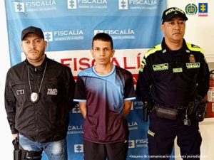 En la fotografía se aprecia de pie y con los brazos atrás a Elkin Andrey Henao Zapata. Viste  camisa de manga corta color uva con azul, pantalón negro y zapatilla blancas. Al lado derecho de él hay un servidor del CTI de la Fiscalía. Al lado izquierdo hay un uniformado de la Policía Nacional. Detrás de ellos hay un pendón institucional de la Fiscalía.