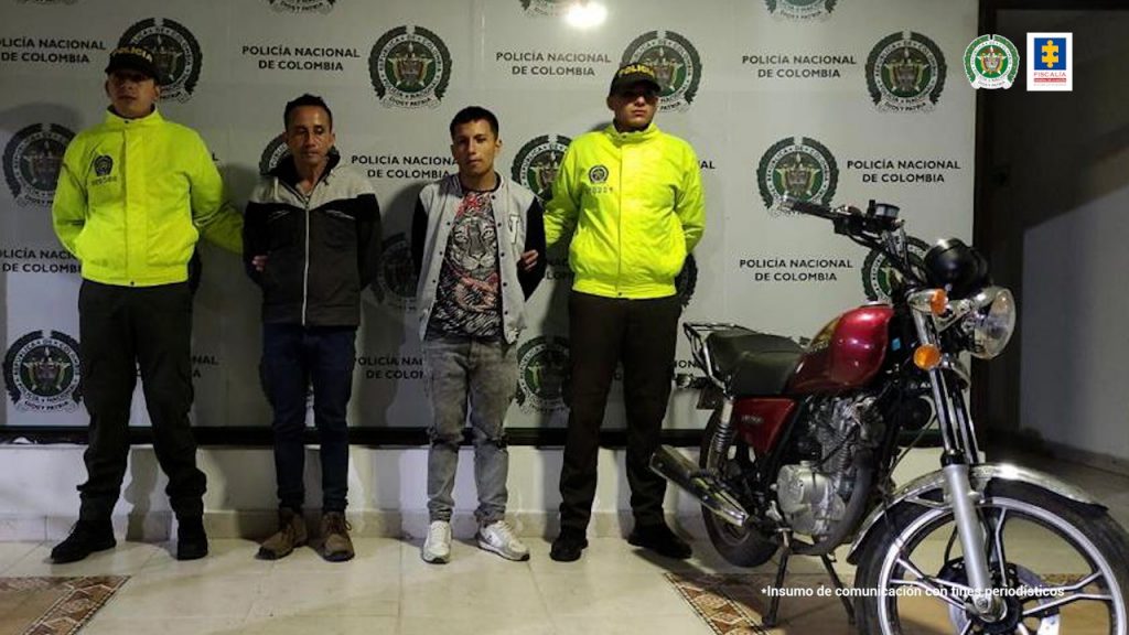 En la fotografía se aprecian de pie y los brazos atrás Elver Chávez Araujo y Heinar De Jesús Ojeda Araujo. Uno viste buz negro con gris a la altura de los hombros, cerrado, así como pantalón negro y zapatos cafés. El otro viste buzo gris con mangas negras largas sin abotonar; camisa con estampado de un tigre; pantalón gris y tenis blancos. A lado y lado de ellos hay uniformados de la Policía Nacional y detrás de ellos hay un pendón institucional de la Policía.