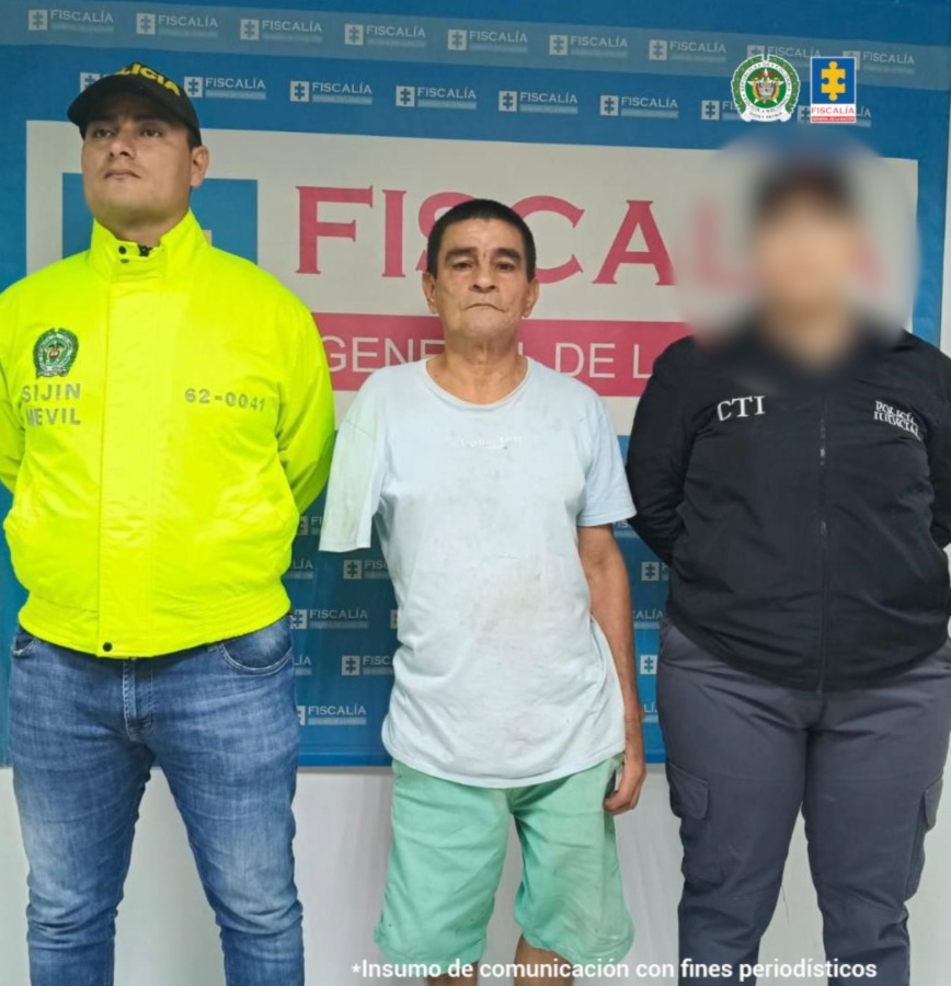 capturado custodiado por investigador del CTI de la Fiscalía y un Policía. Detrás banner de Fiscalía.