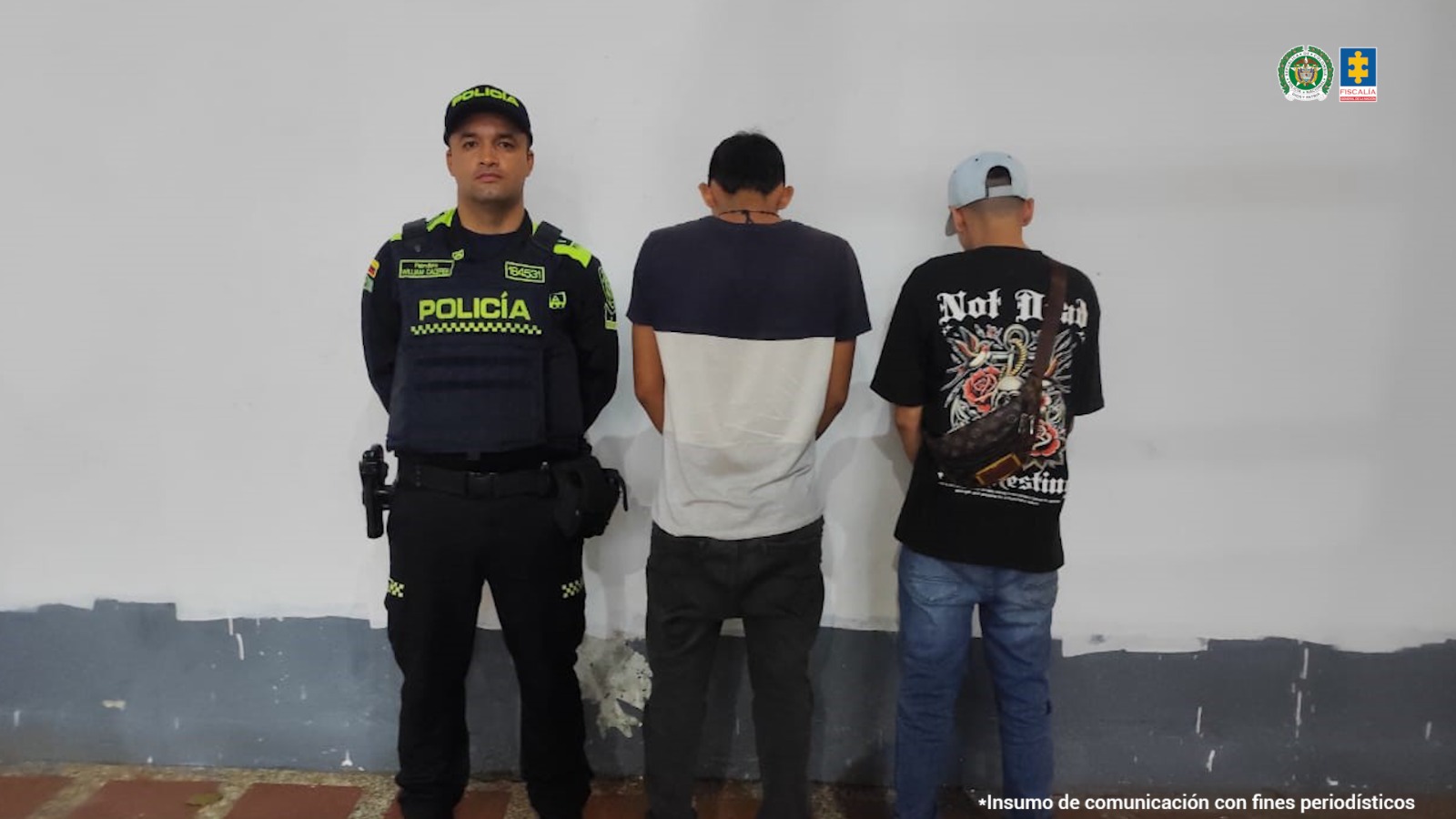 En la fotografía se aprecia de pie y de espaldas a la cámara a Erik Stiven Socha Galvis y Duber Arley Ramírez Barón. Uno viste camisa de manga corta, en la parte superior de color negro y en l prte inferior blanca; pantalón negro y zapatillas blancas. El otro viste camiseta de manga corta de color negro con estampado en la espalada; jean azul y zapatillas negras con zuela blanca. Al extremo izquierdo de ellos hay un uniformado de la Policía Nacional.