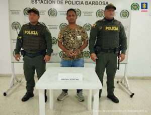 El procesado está con dos servidores de la Policía Nacional que usan uniforme verde oscuro. 