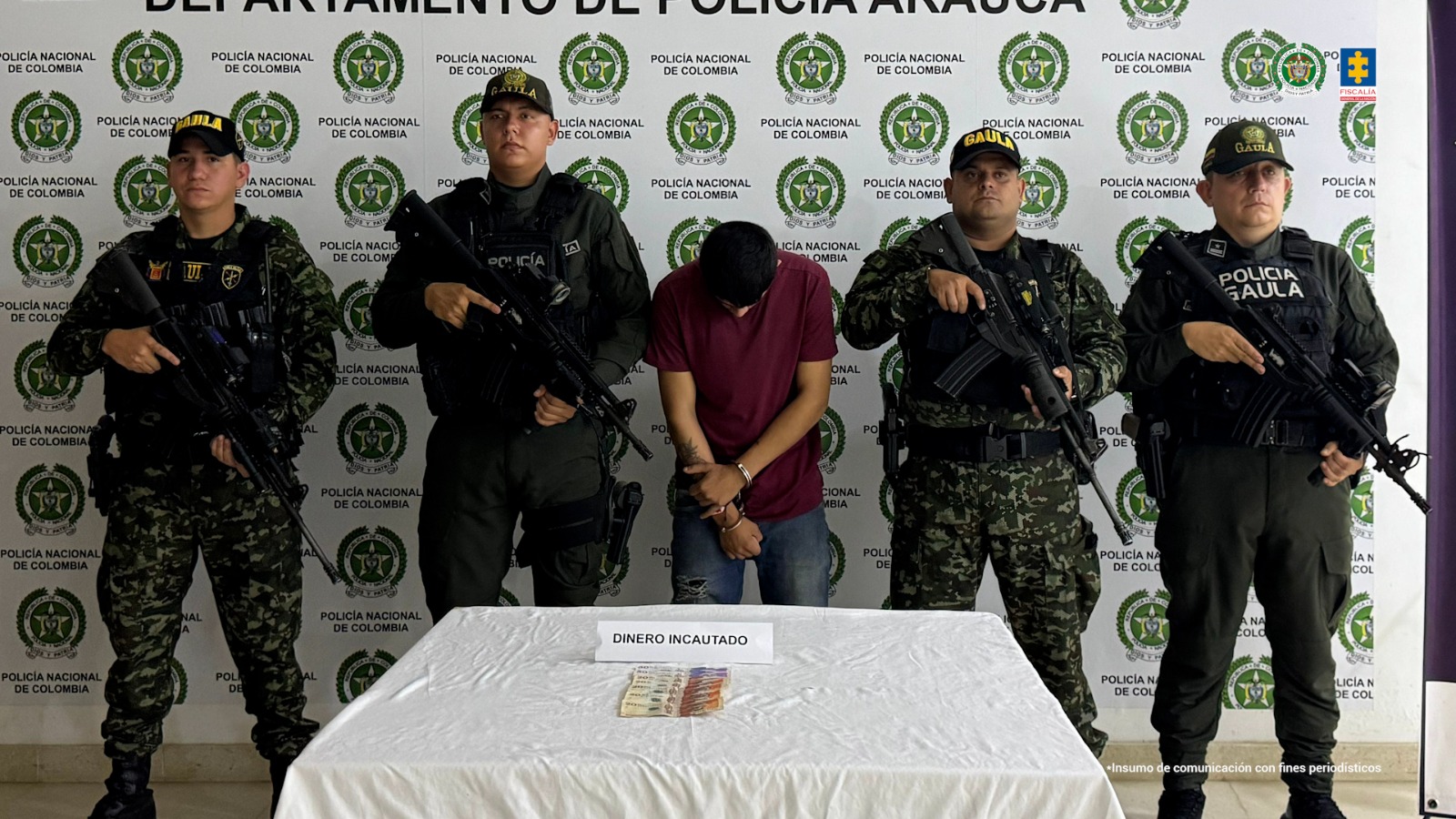 Se visualiza al capturado junto a uniformados del Gaula del Ejército y Policía Nacional. Frente a ellos una mesa con el dinero incautado al momento de la captura. Detrás el banner de la Policía Nacional.