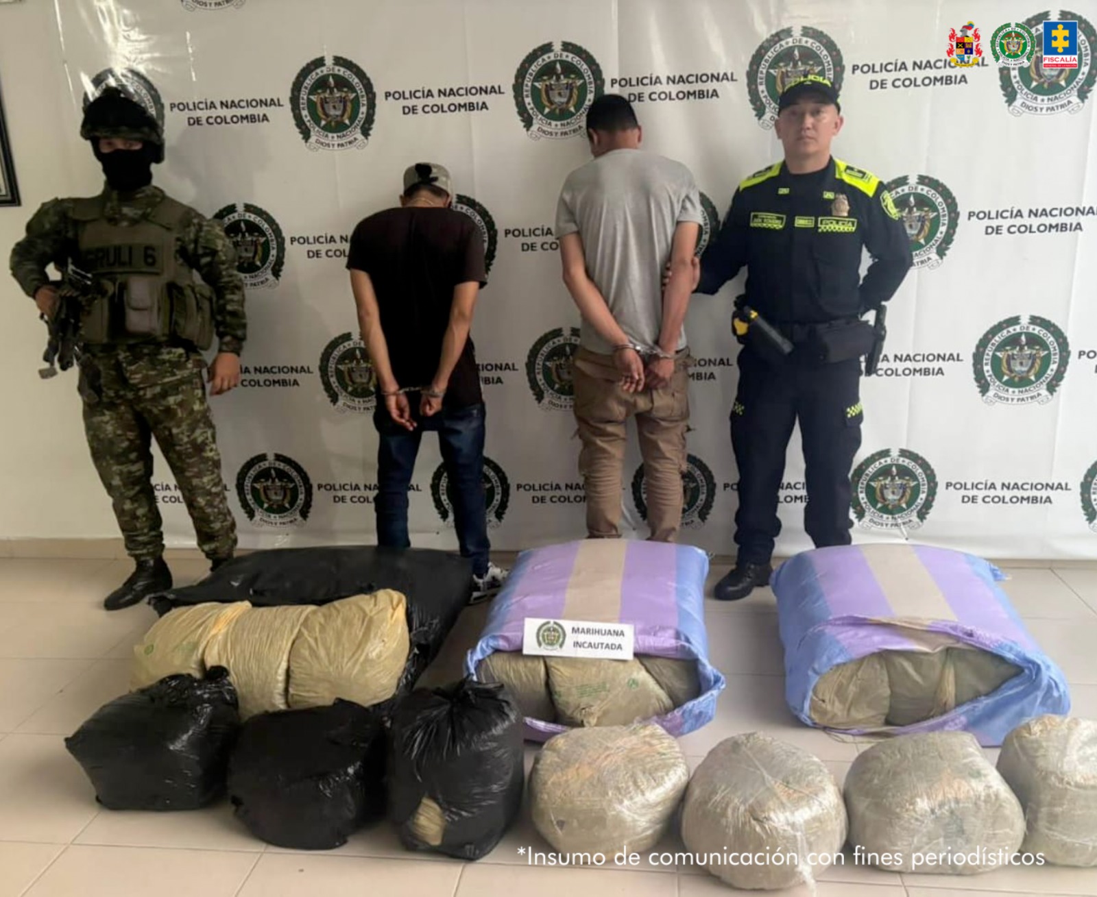 Los capturados se encuentran de espaldas y custodiados por dos uniformados de la Policía Nacional. En la foto se ve de fondo un backing de la Policía Nacional y el estupefaciente incautado.