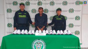 El procesado se encuentra esposado y en custodia por uniformados de la Policía Nacional. Detrás suyo un backing de la Policía y se muestra la mercancía que contenía la caja que se había hurtado.