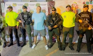 En la fotografía aparece un hombre capturado, acompañado de uniformados de La Policía y el Ejército Nacional. En la parte posterior un banner con logos de la entidad.