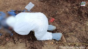 En la foto aparece una servidora de criminalistica del CTI con su traje de protección biológica trabajando en una fosa.