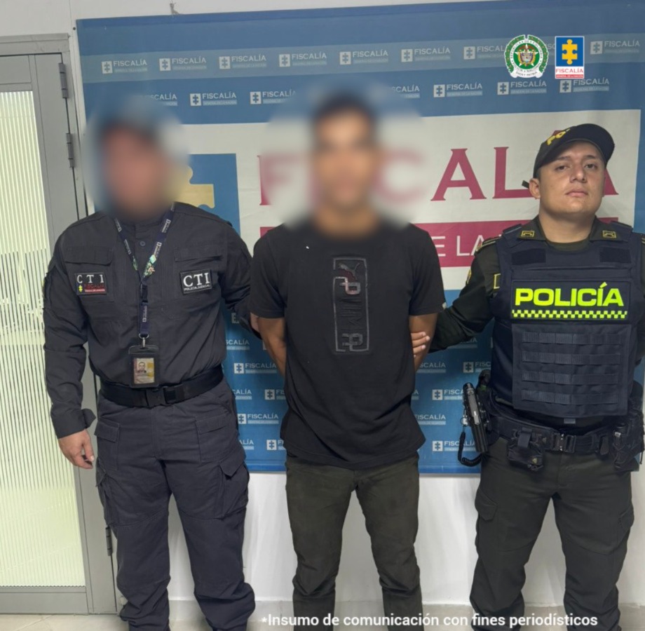 Capturado custodiado por investigador del CTI de la Fiscalía y un Policía. Detrás Banner de la Fiscalía.