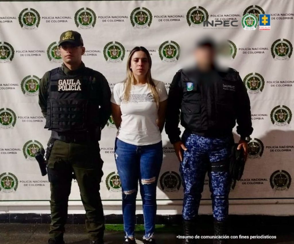 En la foto está la mujer investigada en medio de un patrullero de la policía y un servidor del Inpec.