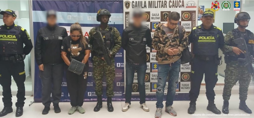 En la fotografía aparecen los capturados junto a dos servidores del CTI, dos agentes de la PoIicía y dos soldados del Gaula Militar. En la parte superior está un banner de la Fiscalía General y del Gaula Militar