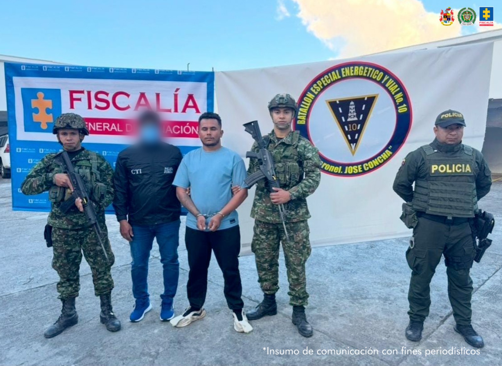 Se observa al capturado junto a un investigador del CTI y uniformados del Ejército y Policía Nacional. Detrás de ellos los banners que identifican a la Fiscalía General de la Nación y al Ejército Nacional.