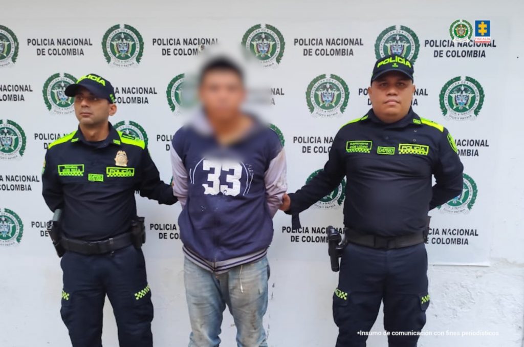 En la imagen aparece una persona detenida de jean con suéter de capota, entre dos uniformados de la Policía Nacional.