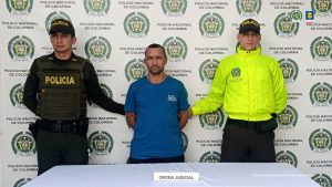 En la imagen aparece el procesado, con camiseta de color azul, en medio de dos uniformados de la Policìa Nacional