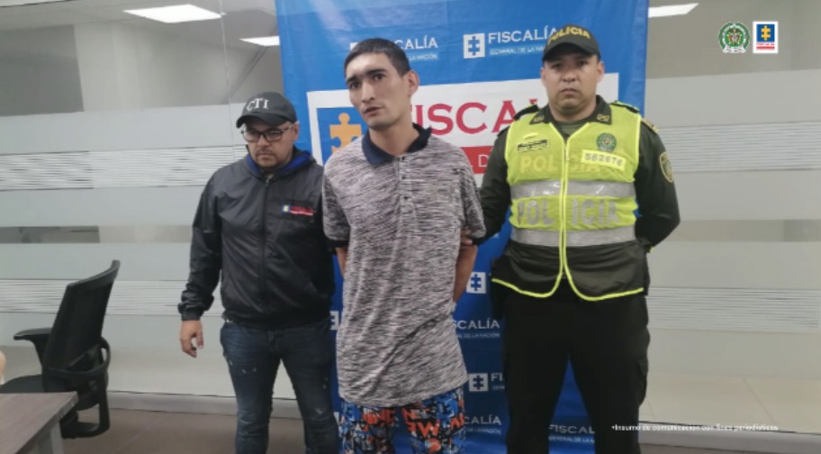 El capturado está esposado a su espalda y está protegido por un servidor del CTI de la Fiscalía y un miembro de la Policía Nacional