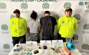 En la imagen aparecen de espalda los capturados, con sus manos esposadas, y en una mesa todos los elementos materiales probatorios incautados durante las diligencias de allanamiento.