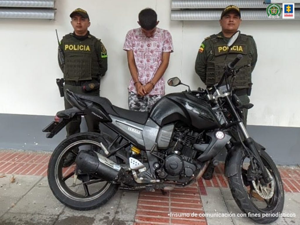 Dúber Arley Ramírez Barón aparece custodiado por dos policías, y la delante de elos está la motocicleta de alto cilindraje recuperada.