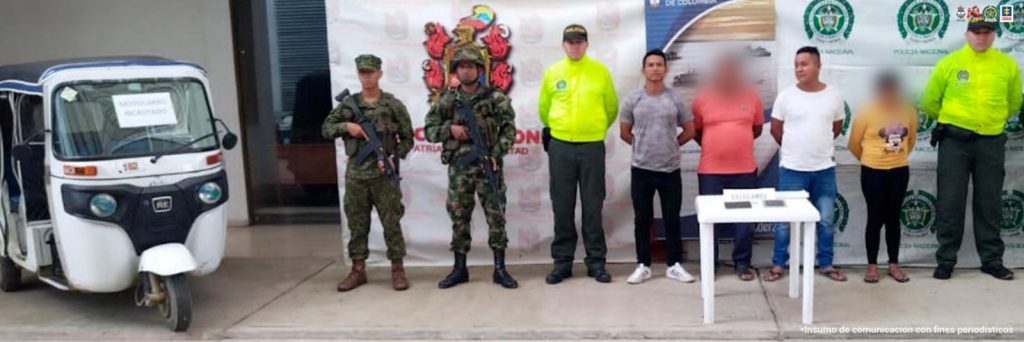 Los capturados aparecen custodiados por uniformados del ejército nacional, la armada nacional y la policía nacional, y en una mesa están varios equipos celulares y en un costado de la imagen, está un motocarro que era utilizado para cometer los ilícitos.
