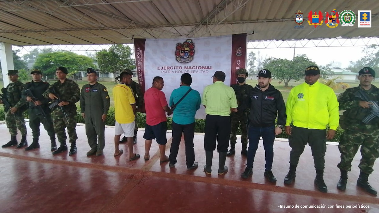 Los capturados aparecen de espaldas y están custodiados por miembros del CTI Fiscalía, la policía, ejército y Fuerza Aérea Colombiana.