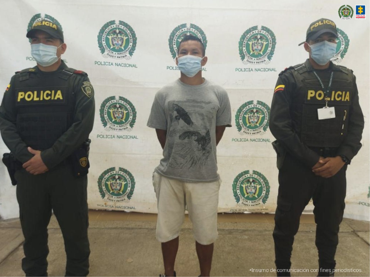 El capturado viste una bermuda blanca y una camiseta gris, está esposado a su espalda y está custodiado por dos unidades de la Policía Nacional.