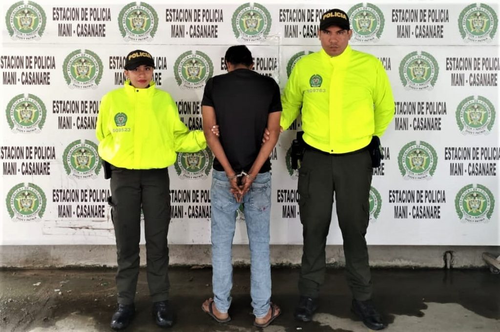 El capturado aparece de espalda a la cámara y está rodeado de dos uniformados de la policía nacional.