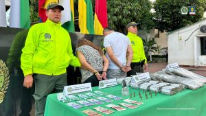 En la foto se observa parte de la marihuana incautada ya dosificada lista para ser comercializada, también se observa el dinero incautado, el arma y la munición. También se observan de fondo los dos capturados.