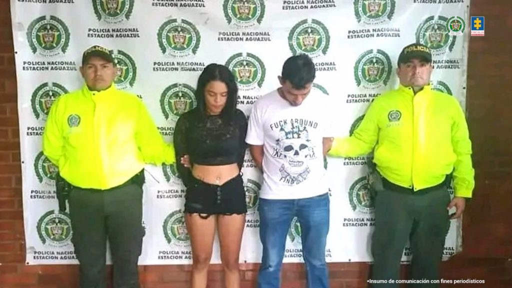 Los capturados tienen sus rostros agachados, y están en medio de dos uniformados de la Policía Nacional. 