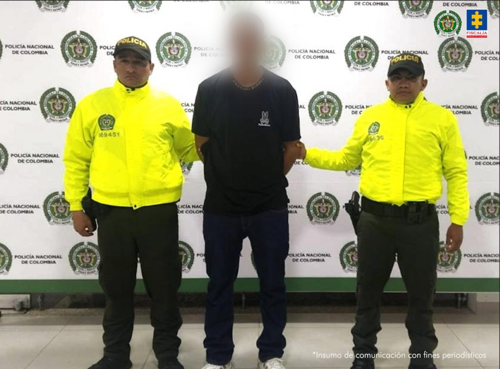 El capturado aparece de frente a la cámara, está vestido de negro y con sus manos esposadas a la espalda, lo custodian dos uniformados de la Policía Nacional.
