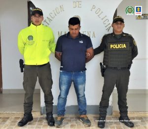 El capturado aparece en medio de dos uniformados de la policía, y deberá responder por el delito de homicidio agravado.
