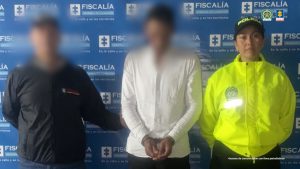 Los hombres aparecen con sus manos esposadas y custodiados por uniformados de la policía nacional. 