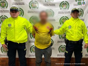El condenado aparece esposado y custodiado por dos uniformados de la policía nacional.