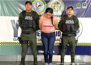 La capturada aparece custodiada por uniformados de la policía nacional y esposada con sus manos a la espalda.