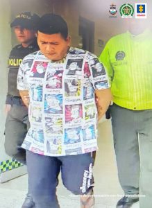 El capturado aparece siendo conducido por dos uniformados de la policía nacional, está esposado a su espalda.