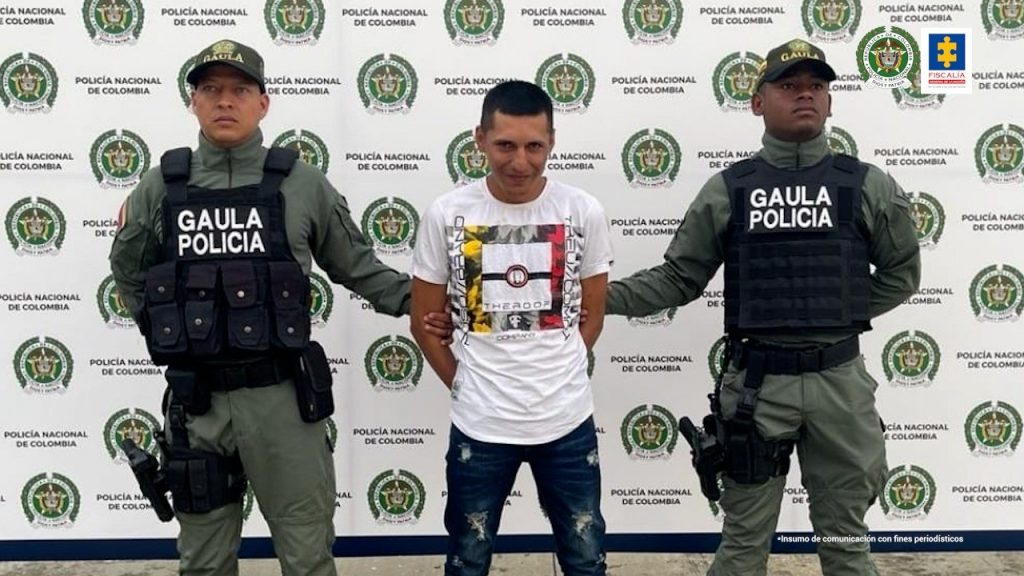 En la fotografía aparece el capturado junto a dos agentes de la Policía Nacional. En la parte superior está un banner de la Policía Nacional