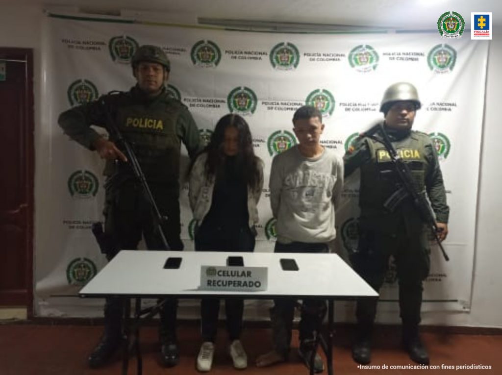 En la fotografía se observa a la pareja junto a dos agentes de la Policía Nacional. En la parte superior se observa un banner de la Policía Nacional.