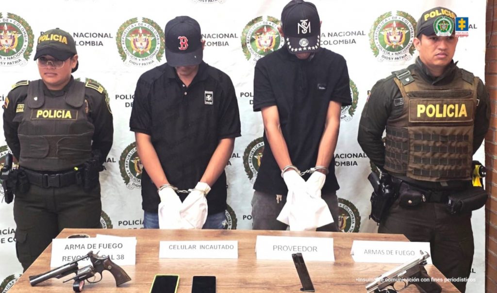 Los dos capturados aparecen de frente a la cámara con su rostro agachado y oculto por las gorras que tienen puestas, sus manos están esposadas y envueltas en bolsas especiales para practicarles la prueba de absorción.En una mesa frente a ellos, están las xrmas de fuego que presuntamente utilizaron en el atentado, así como dos celulares.