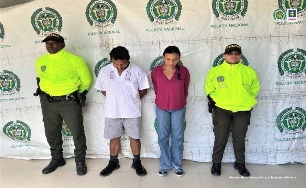 Los capturados aparecen esposados a la espalda y custodiados por dos uniformados de la Policía Nacional.