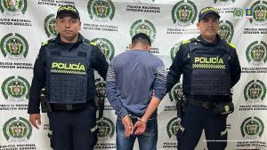 El capturado aparece de espalda a la cámara, está custodiado por uniformados por uniformados de la Policía.