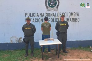 El capturado aparece de espalda frente a la cámara y está custodiado por dos uniformados de la Policía Nacional.