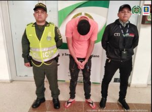 El capturado aparece en la imagen esposado, con la cabeza agachada y custodiado por servidores de la policía y la Fiscalía.