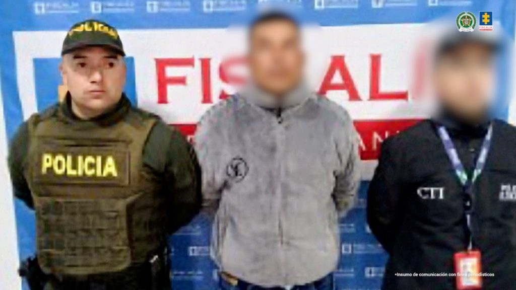 En la fotografía aparece el capturado junto a un servidor del CTI y un integrante de la Policía. En la parte superior está un banner de la Fiscalía General