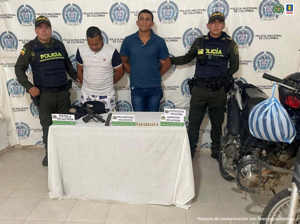 En la fotografía aparecen dos personas capturadas, junto a dos uniformados de la Policía Nacional. En la parte posterior se ve un banner de la misma entidad.