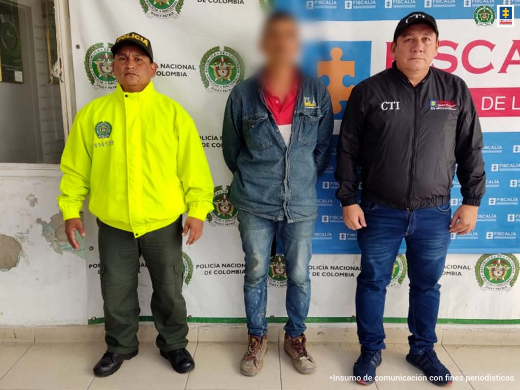 En las fotografía aparece un capturado, junto a personal de CTI y Policía Nacional. En la parte posterior de la imagen se ven banners de Policía Nacional y la Fiscalía General de la Nación.