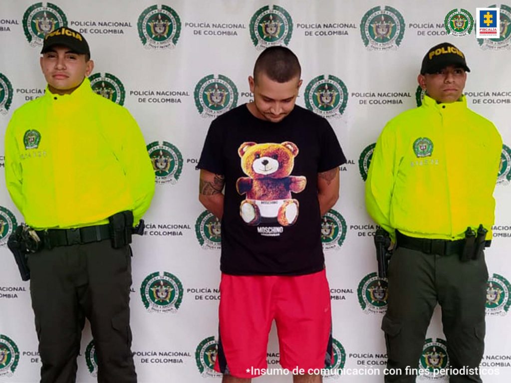 En las fotografía aparece un capturado, junto a personal de Policía Nacional. En la parte posterior de la imagen se ven banners de Policía Nacional y la Fiscalía General de la Nación.