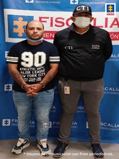 En la fotografía aparece el capturado, junto a investigador del CTI. En la parte posterior se encuentra un banner de la Fiscalía General de la Nación.