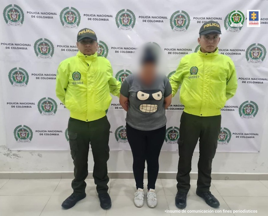 En la fotografía aparece una mujer capturada junto a dos agentes de la Policía de Ipiales. En la parte posterior se ve un banner de la Policía Nacional