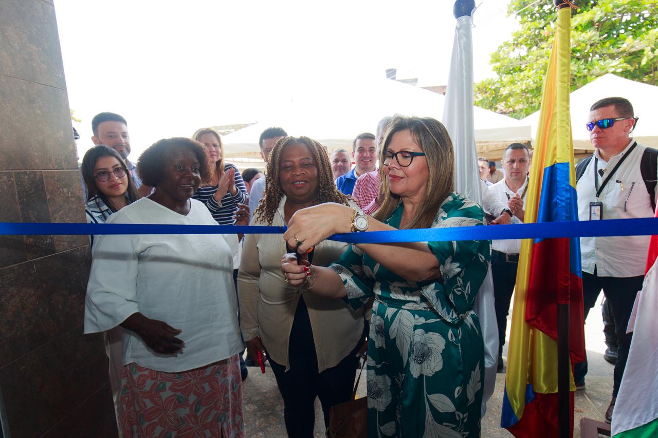 La Fiscal General, Luz Adriana Camargo, corta una cinta azul. La acompañan unas mujeres y se ven otras personas en el fondo, además de banderas de Fiscalía y Colombia. 