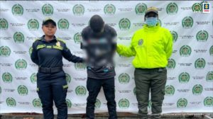 Fiscal Mancera, Fiscal Martha Mancera, Martha Mancera, Fiscalía General de la Nación Adolfo Lagarejo Brivas, alias Revelo, acompañado por dos funcionarios de la Policía Nacional y el pendón de la misma Institución.