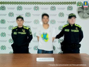 Fiscal Mancera, Fiscal Martha Mancera, Martha Mancera, Fiscalía General de la Nación En las tres fotografías se observa al capturado en el centro y a cada costado un uniformado de la Policía Nacional. Atrás un pendón de Policía Nacional y delante una mesa en la cual está expuesto el material incautado.