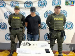 Fiscal Mancera, Fiscal Martha Mancera, Martha Mancera, Fiscalía General de la Nación En las tres fotografías se observa al capturado en el centro y a cada costado un uniformado de la Policía Nacional. Atrás un pendón de Policía Nacional y delante una mesa en la cual está expuesto el material incautado.