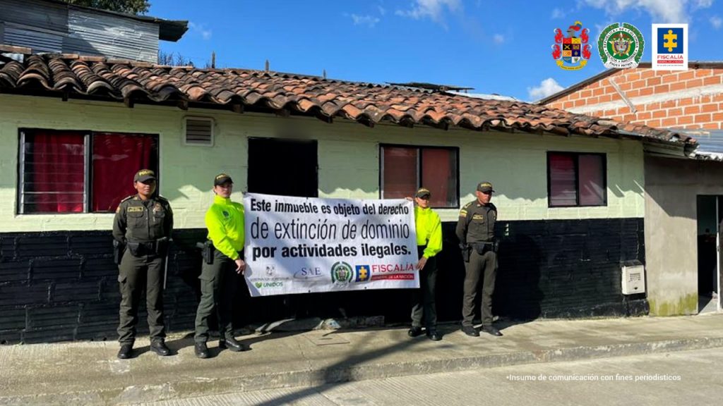 En la imagen se aprecian cuatro uniformados de la policía nacional, resguardando un bien que fue afectado con medidas cautelares por presuntamente ser de personas, al parecer, implicadas en actividades ilegales. dos de los policiales sostienen un cartel en el que se aprecian logos de las entidades que participaron en los operativos.